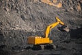 Large yellow excavator with full bucket of black coal will carry out loading in open mine