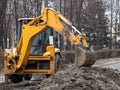 A large yellow excavator stands in the middle of the street near the dug hole Royalty Free Stock Photo