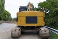 A large yellow excavator visible from the rear, standing on concrete.