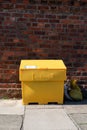 Large yellow grit salt container on pavement sidewalk Royalty Free Stock Photo
