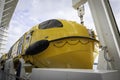 Large yellow lifeboat on side of cruise ship