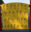 Yellow sign language alphabet guide board on children`s playground Royalty Free Stock Photo