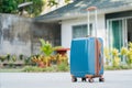 larger plastic suitcase with wheels on the background of a summer house. Royalty Free Stock Photo