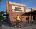 Larger than life-size metal statue of a human-like creature holding a pizza slice in its right hand in Arlington, Texas.