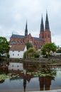 Old monument cathedral in the city of Uppsala in Sweden with lake and reflection on the surface.