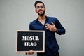Arab man wear blue shirt and eyeglasses hold board with Mosul Iraq inscription. Largest cities in islamic world concept