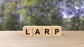 Larp word wooden cubes on table vertical over blur background with trees green sky, mock up, template, banner with copy space for