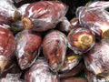 Banana blossoms wrapped in plastic in the fresh produce section of a store