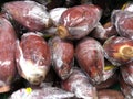 Close up of banana blossom wrapped in plastic in the fresh produce section of a store