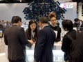 Young female exhibitors assist businessmen at the Royole counter at CES