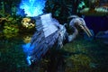 large blue bird sculpture in a water fountain, colorful animal art in an artificial tropical garden