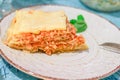 Lasagna bolognese slice on a white patterned plate with basil and fork on table Royalty Free Stock Photo