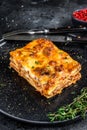 Lasagna with mince beef meat and tomato bolognese sauce on a plate. Black background. Top view Royalty Free Stock Photo