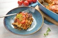 Lasagna portion in a blue plate, casserole dish with pasta layers, Bolognese sauce, ground beef, vegetables and tomatoes, topped Royalty Free Stock Photo