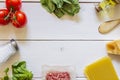 Lasagna, tomatoes, minced meat and other ingredients. White wooden background. Italian cuisine