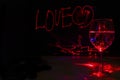 Laser light painting of Love sign for valentines day in a dark background with wine glass for the celebration Royalty Free Stock Photo