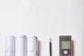 Laser meter, pencil and rolled drawings at blank white background with copy space Royalty Free Stock Photo