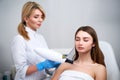 Laser mole removal on a woman`s chest in a beauty salon. Hardware cosmetology. Pretty blonde beautician doctor removing Royalty Free Stock Photo