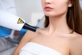 Laser mole removal on a woman`s chest in a beauty salon. Hardware cosmetology. Beautician doctor removing birthmark or Royalty Free Stock Photo