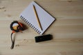 Laser range finder, tape measure, notebook, pencil on a light background