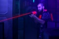 Laser Tag Player Holding Gun Shooting Light In Black Light Labyrinth
