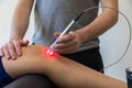 Laser therapy on a knee used to treat pain.