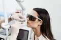 Laser treatment of chronic rhinitis. ENT doctor with laser treats girl patient in protective glasses. Laser treatment Royalty Free Stock Photo