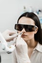 Laser treatment of chronic rhinitis. ENT doctor with laser treats girl patient in protective glasses. Laser treatment Royalty Free Stock Photo