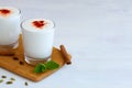 Lassi drink with red pepper and fresh green mint on wooden board.