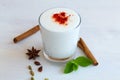 Lassi drink with red pepper and fresh green mint on wooden board.