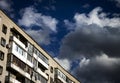 The last floors of a brick multi-story building against the background of a blue sky with white clouds Royalty Free Stock Photo