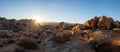 Last light of sunset behind rocks and bouldrs in panoramic view of desert landscape on a sunny January day with clear blue sky in