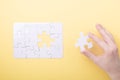 Last piece jigsaw in hand White puzzle Concept success of business Yellow background Royalty Free Stock Photo