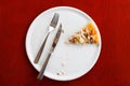 Last piece of pizza on a white plate. Wooden table knife and fork. Royalty Free Stock Photo