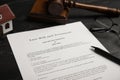 Last will and testament near house model, glasses, gavel on black table, closeup Royalty Free Stock Photo