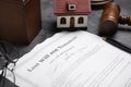 Last will and testament near house model, glasses and gavel on grey table, closeup Royalty Free Stock Photo