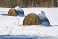 Last year`s hay bales with snow caps on a snowy field, March day. Russia Royalty Free Stock Photo