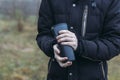 In late autumn, men`s hands are warming themselves on a black toggle switch with a hot drink. Environmentally friendly use of Royalty Free Stock Photo