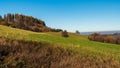 Late autumn rolling landscape with meadows, isolated cottage, forest and clear sky