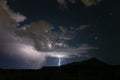 A late bolt of lightning from a thunderstorm as it drifts away leaving a starry sky Royalty Free Stock Photo