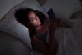 late-night woman in bed, captivated by her phone screen, insomnia and smartphone dependency.