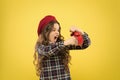 She is late for school. Small child punching alarm clock with anger on yellow background. Angry little girl fighting