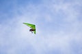 Man on green motorized hang glider is enjoying his flight.