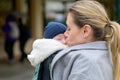 Late-term mother in her 40s lovingly holding her newborn baby in a baby carrier and kissing him gently Royalty Free Stock Photo