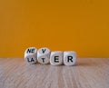 From later to never symbol. Turned a cube and changes the word later to never. Beautiful wooden table, orange background. Business