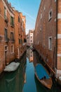 Lateral canal with docked boats in Venice, Italy. Reflections and ble sky