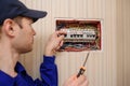 Young electrician in blue overall disassembling a electrical panel with fuses in a house