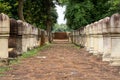 Laterite stone paved walkway with free-standing stone posts to the gates of ancient Khmer temple built of red sandstone and lateri