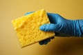 Latex gloved hand, isolated, grips a dishwashing sponge for sparkling, sanitized dishes