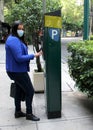 Latin adult woman with protection mask paying public parking on the street, new normal covid-19 Royalty Free Stock Photo